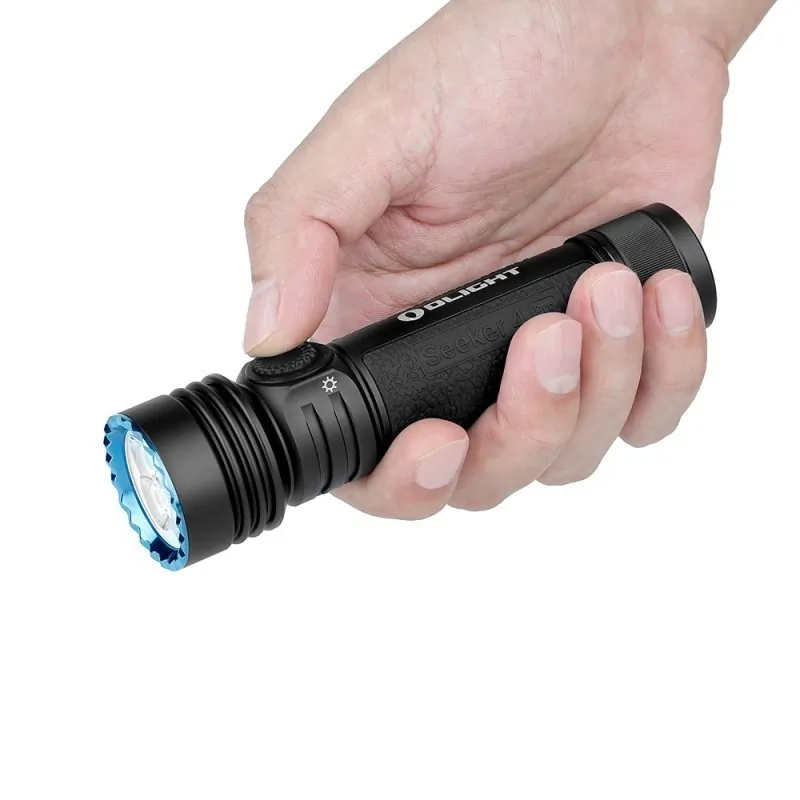 Lampe Olight Seeker 4 Pro noire tenue en main, pouce sur le bouton